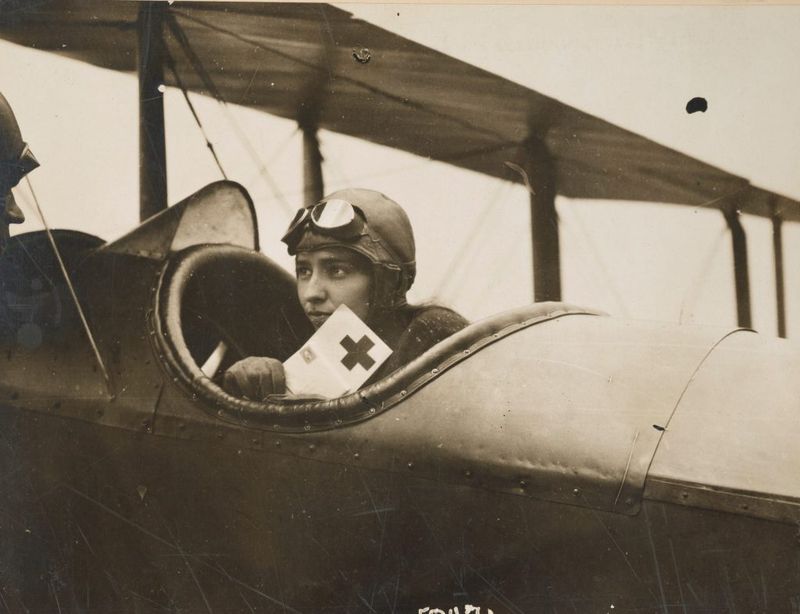 A female pilot in full gear beside her biplane, 1927