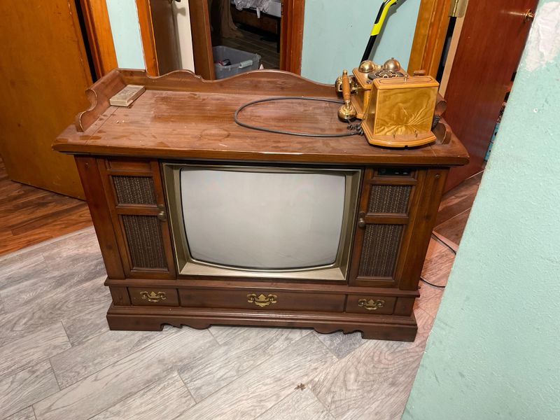 A TV with Rabbit Ears and a Wood Cabinet