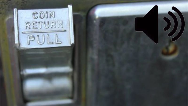 The rattle of coins in a payphone drop slot